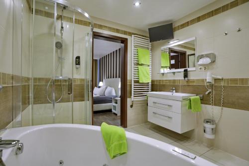 a bathroom with a tub and a shower and a sink at VITALHOTEL Schulenberg in Schulenberg im Oberharz
