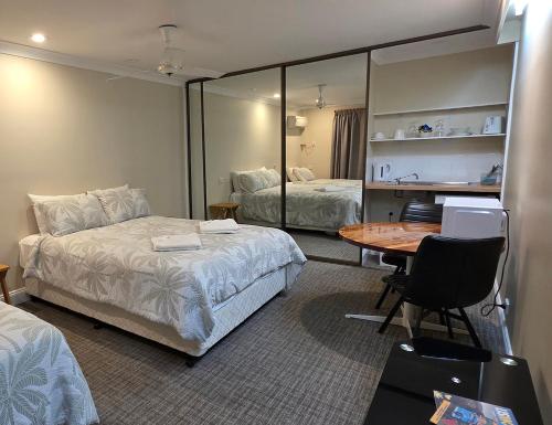 a hotel room with two beds and a table and mirror at Sisleys Motel in Lismore