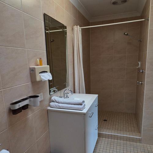 a bathroom with a sink and a shower at Sisleys Motel in Lismore