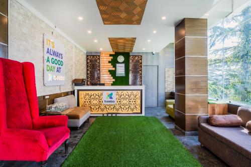 a lobby with a red chair and a green rug at Treebo Holiday Hill in Dharmsāla