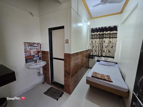 a small room with a bed and a sink at Hotel Shreejay Lodging in Mahād
