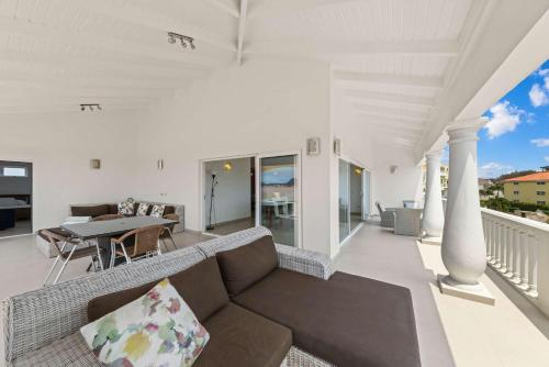 a living room with a couch and a table on a balcony at Blue Horizon Penthouse in Dorp Sint Michiel