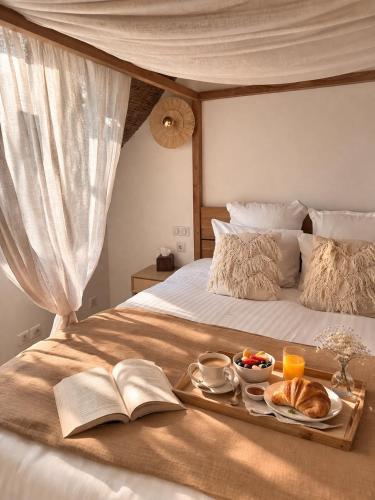 a tray of food on a bed with a book at La maison Balinaise in Haravilliers