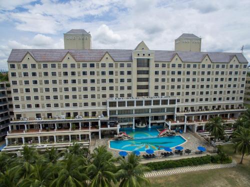 a large hotel with a large pool and palm trees at Corus Paradise Resort Port Dickson in Port Dickson