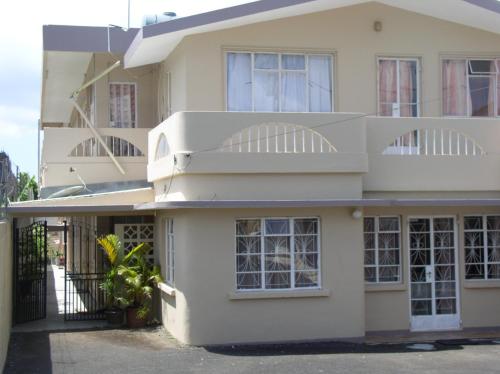a large white house with a balcony at BR Apartment & Studios in Curepipe