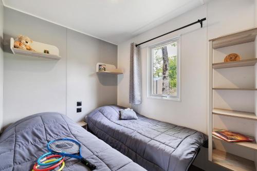 a bedroom with two beds and a window at Mobilehome riviera avec terrasse 48 in Saint-Gervais