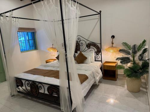 a bedroom with a canopy bed and a potted plant at cali stays in Chapora