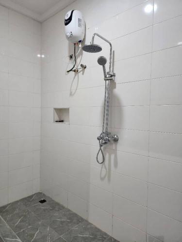 eine weiß geflieste Dusche mit einem Haartrockner an der Wand in der Unterkunft The Bubbles Hotel in Akobo