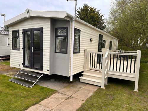 a white tiny house with a porch and a staircase at Sylvia's Sunrise Caravan Skegness Southview in Winthorpe