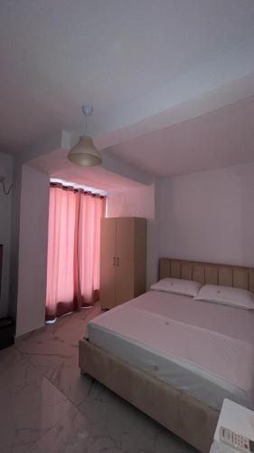 a bedroom with a large bed and pink curtains at ApartHotel XH in Golem