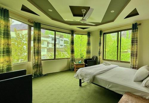 a bedroom with a bed and large windows at Flora Inn Skardu in Skardu
