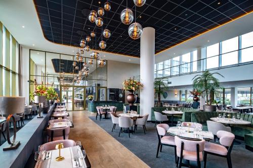 a restaurant with tables and chairs and windows at OZO Hotels De President Amsterdam Schiphol Airport in Hoofddorp