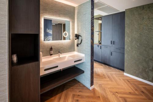 a bathroom with a sink and a mirror at OZO Hotels De President Amsterdam Schiphol Airport in Hoofddorp