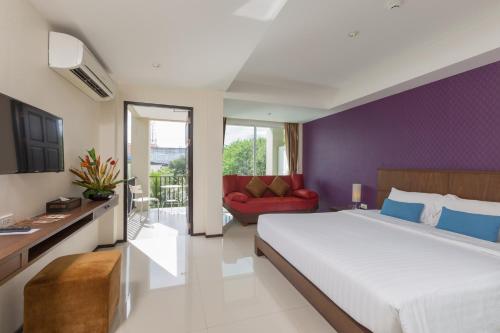 a bedroom with a large bed and a red chair at Lub Sbuy House Hotel - SHA in Phuket Town