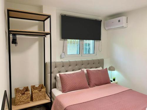a bedroom with a bed with pink sheets and a window at Nikol's central suite 1 in Nea Peramos