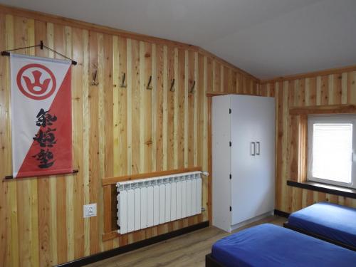 a bedroom with wooden walls and a refrigerator and a window at Pokoje pod Turbaczem in Ostrowsko