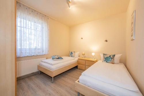 two beds in a small room with a window at Ferienwohnung Krebs in Loddin