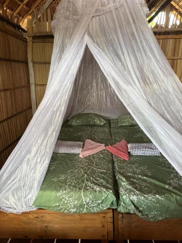 a bed in a tent with white mosquito nets at West Waigeo Bungalow in Kabu