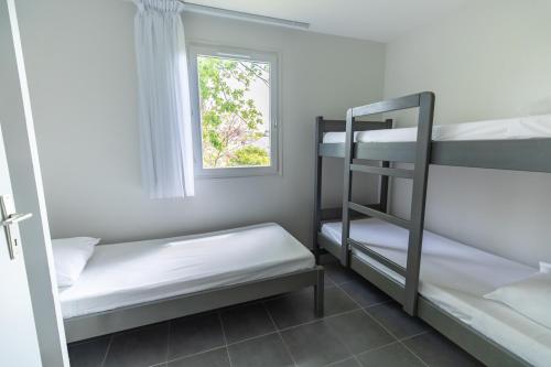a room with two bunk beds and a window at Village Beauséjour - Rêves de mer in Le Conquet
