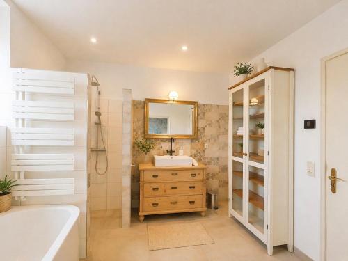 a bathroom with a sink and a tub and a mirror at Finca Ludwig am Forggensee in Rieden