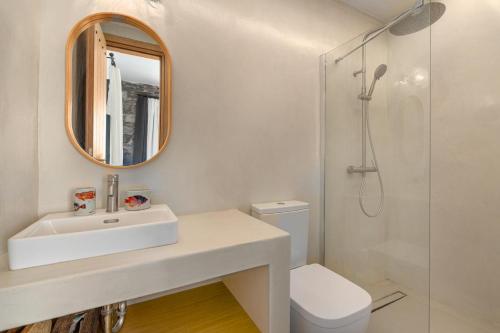 a white bathroom with a sink and a mirror at Ikos Kythnos in Kithnos