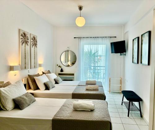 a large bedroom with two beds and a mirror at Thalassa Garden Studios in Pefkochori