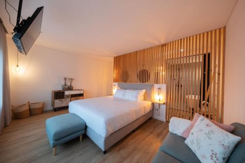 a bedroom with a white bed and a blue couch at Chez Nous I e II in Caloura