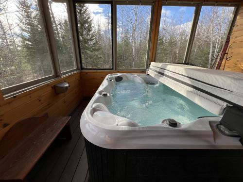 a large bath tub in a room with windows at Spa & Pool Table - L Experience in Petite-Rivière-Saint-François