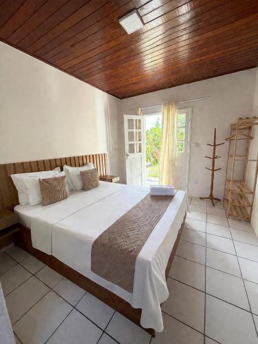 a bedroom with a large bed with a wooden ceiling at Pousada Coco Dendê in Ilha de Boipeba