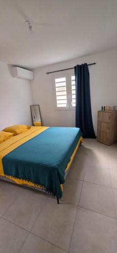 a bedroom with a bed with a blue and yellow blanket at Anse a l ane in Les Trois-Îlets