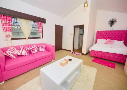 a living room with a pink couch and a bed at Cutie Studio Unit Nyali in Mombasa