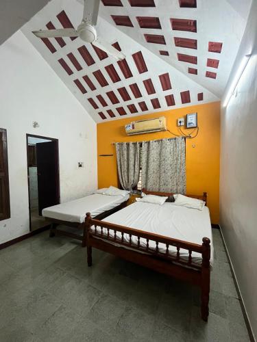 two beds in a room with a ceiling at Gravity Groups SSK - Near Sangamithra Jipmer in Puducherry Airpoert