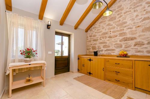a kitchen with wooden cabinets and a stone wall at House Bilusic in Poljica