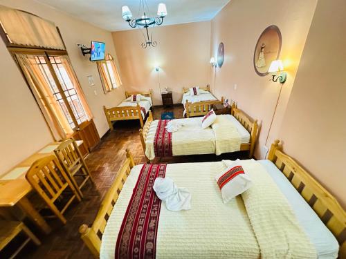 a hotel room with two beds and a table at Hostal La Posada De La Abuela in La Paz