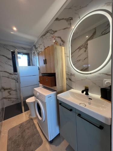 a bathroom with a washing machine and a sink at Les Appartements chez Hanene in Le Grau-du-Roi