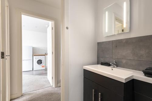 a bathroom with a sink and a washing machine at Thornhill House by Guestz in Wakefield