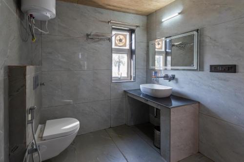 a bathroom with a sink and a toilet and a mirror at Kaafal Cottage in Mukteshwar