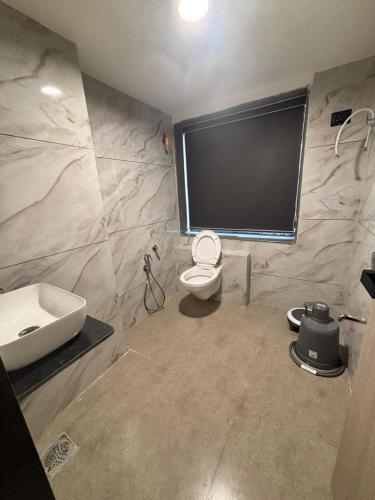 ein Badezimmer mit Waschbecken, Toilette und Fernseher in der Unterkunft Hotel Pine Ville in Ahmedabad