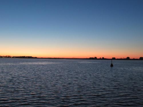 a sunset over a large body of water at Hausboot Isa - Huus & Meer in Heiligenhafen