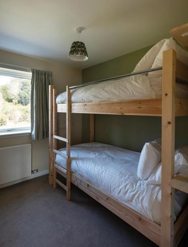 a bedroom with two bunk beds and a window at Sunny Ridge in Fort Augustus