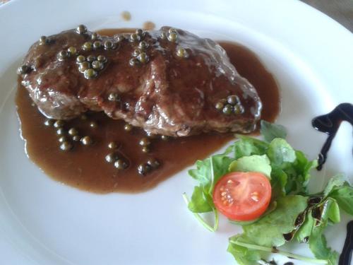 a plate of food with meat and sauce and a salad at Grobelnik Tourist Farm in Sevnica