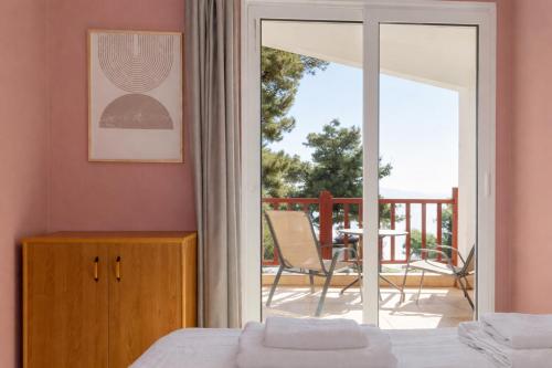 a bedroom with a bed and a balcony with a table at Sunset Cove by halu! - Spacious 4-bedroom Villa in Neos Marmaras