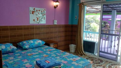 a bedroom with a bed and a sliding glass door at Rueangsrisiri Guesthouse 2 in Sukhothai