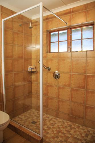 a shower with a glass door in a bathroom at Gooderson Leisure Riverbend Chalets Self Catering in Drakensberg Garden