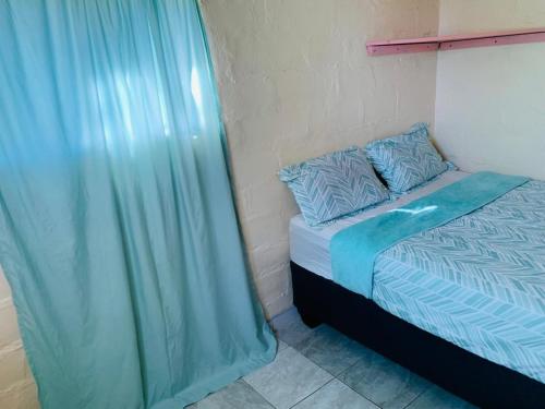 a bedroom with a bed and a blue curtain at Mountain View Escape in Mbabane