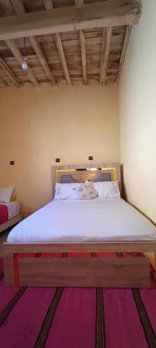 a bedroom with a large bed with white sheets at Diafat ISSIRIDEN in Tazrouft