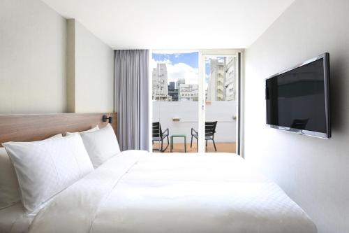 a hotel room with a bed and a flat screen tv at Cityinn Hotel Taipei Station Branch I in Taipei