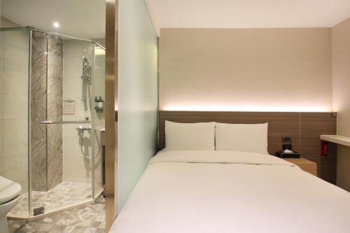 a bedroom with a bed and a glass shower at Cityinn Hotel Taipei Station Branch I in Taipei