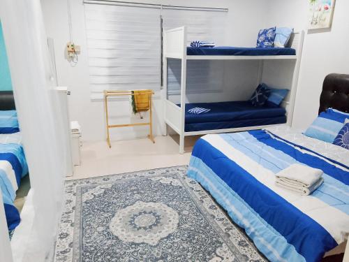 a bedroom with two beds and a couch in it at Aura Bluewave Beach House, Chenang in Pantai Cenang