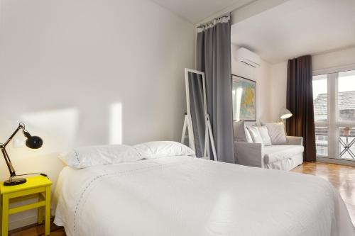 ein weißes Schlafzimmer mit einem weißen Bett und einem Stuhl in der Unterkunft Fabrica Apart in Porto